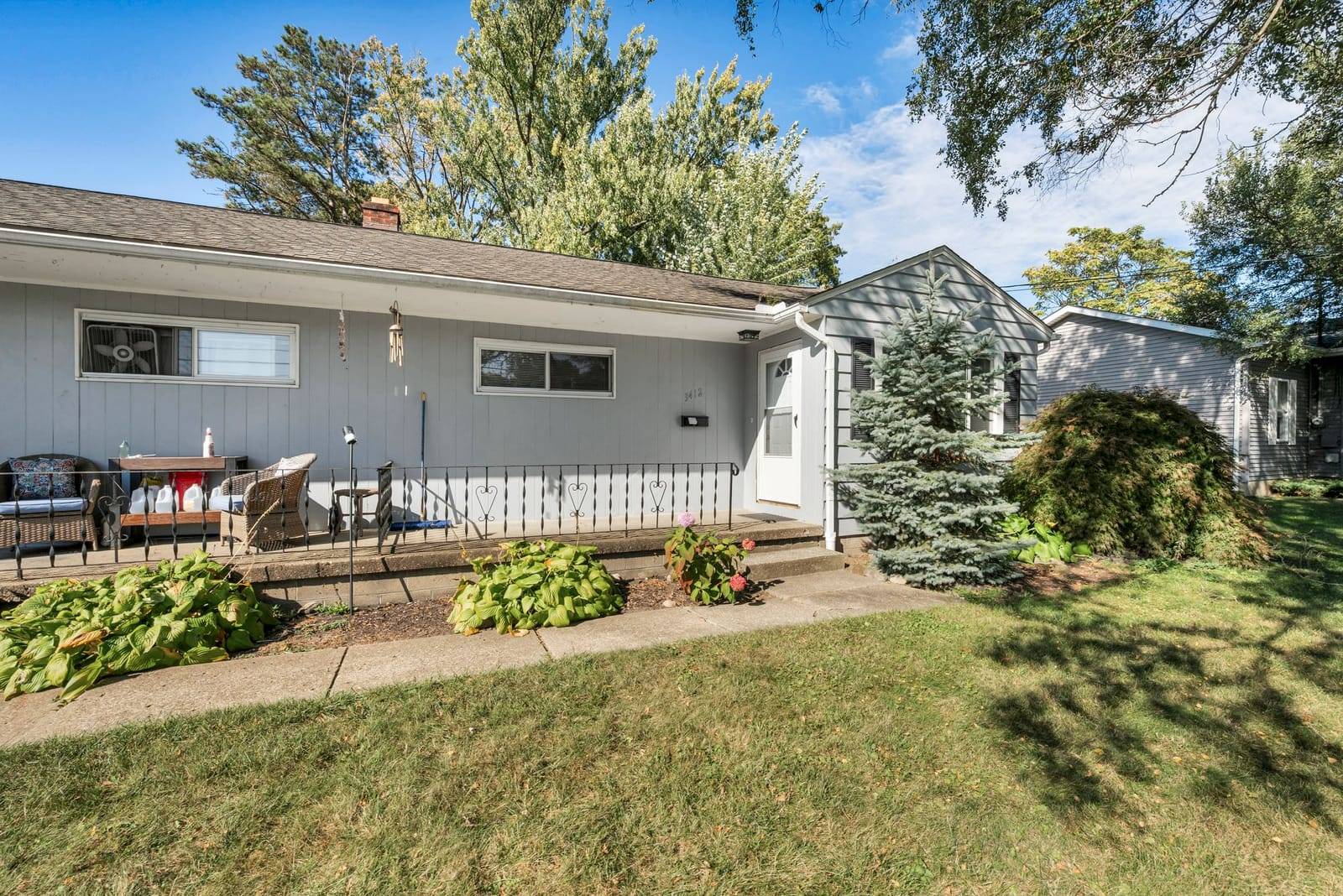 Single-story house with a front porch, shrubs and a lawn